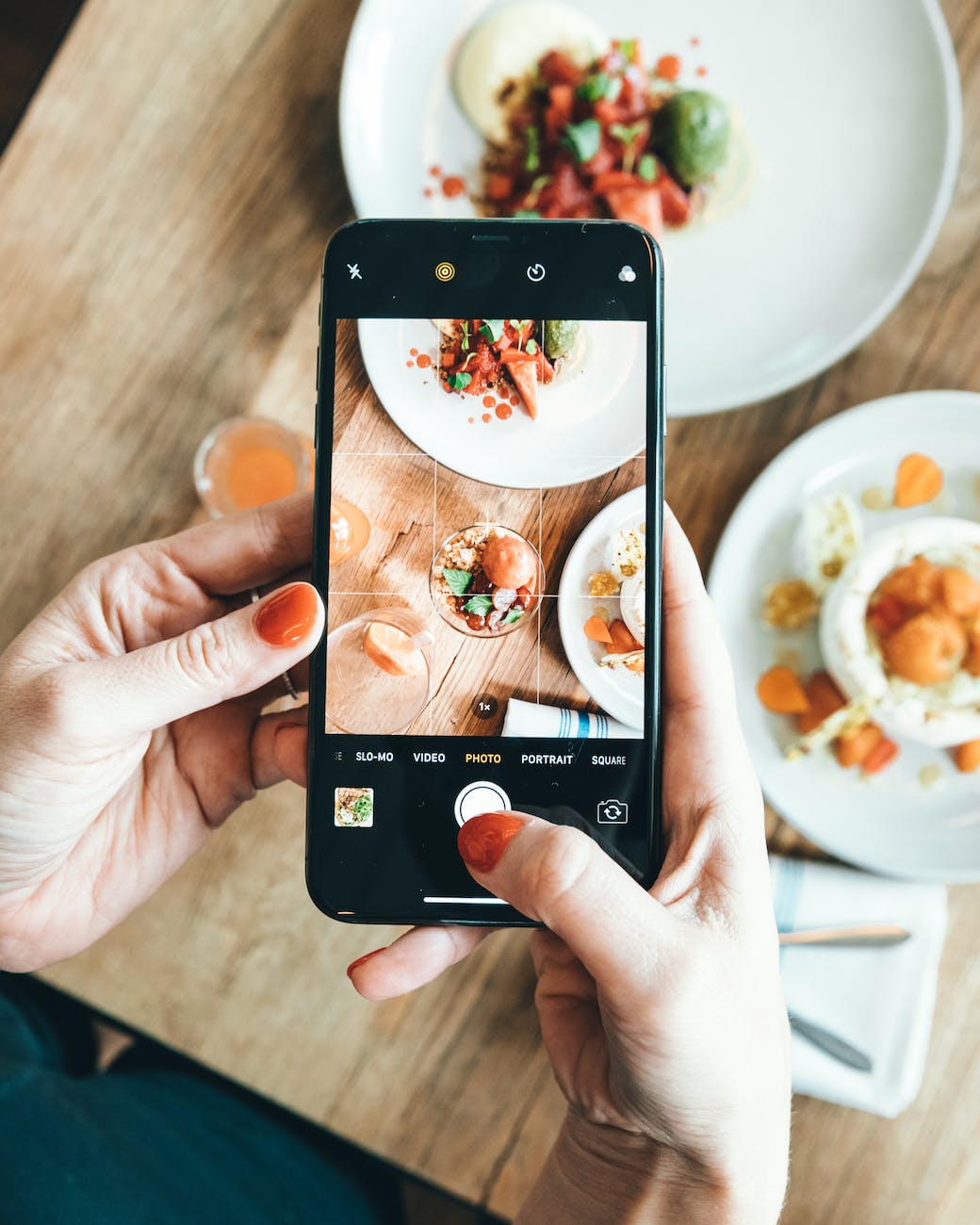 a person holding black mobile phone taking photo of food